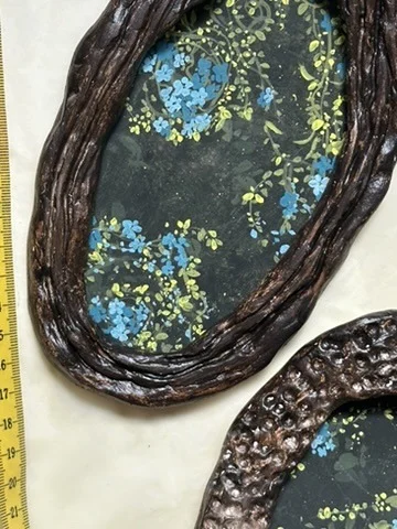 Two hand-built ceramic frames with a tape measure, ready for painting